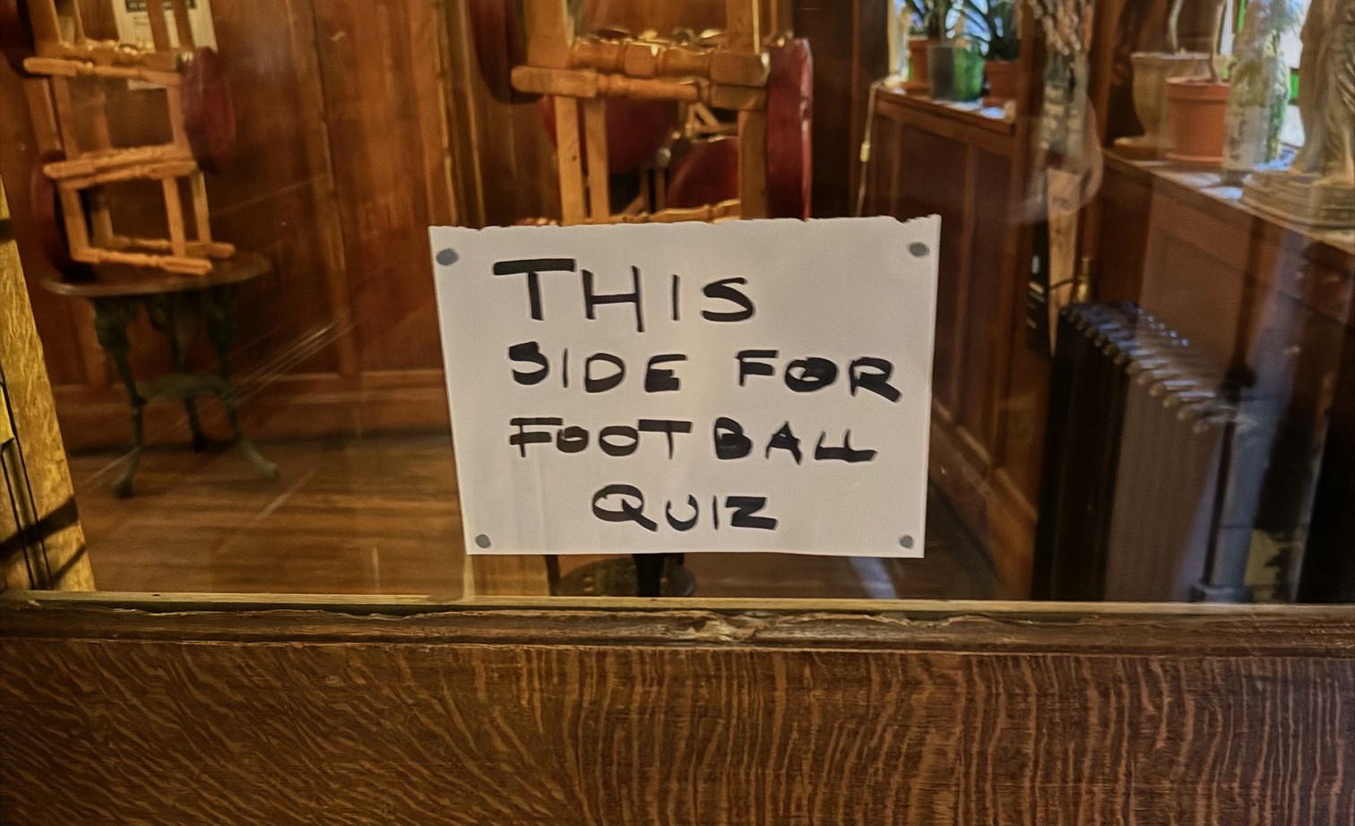 A sign on a pub door saying "this way for football quiz"